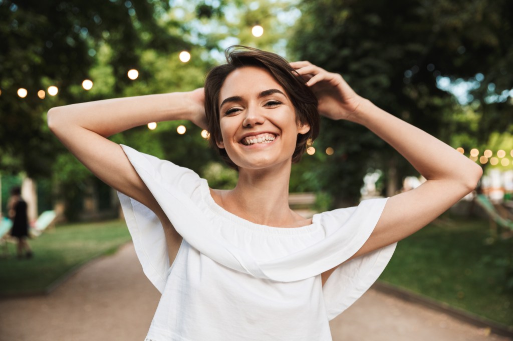 Smiling happy girl looking at camera while standing at the park